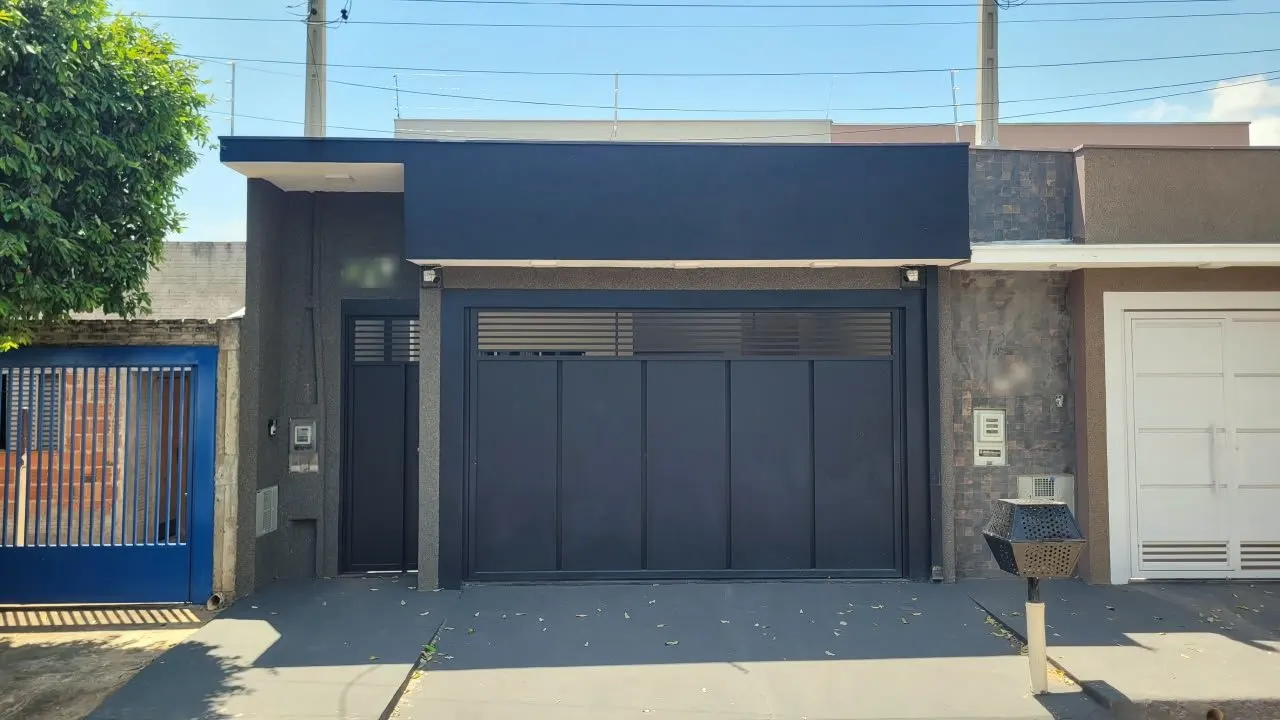 Fachada de casa térrea pintada de azul marinho, com portão de garagem largo e porta social na mesma cor.